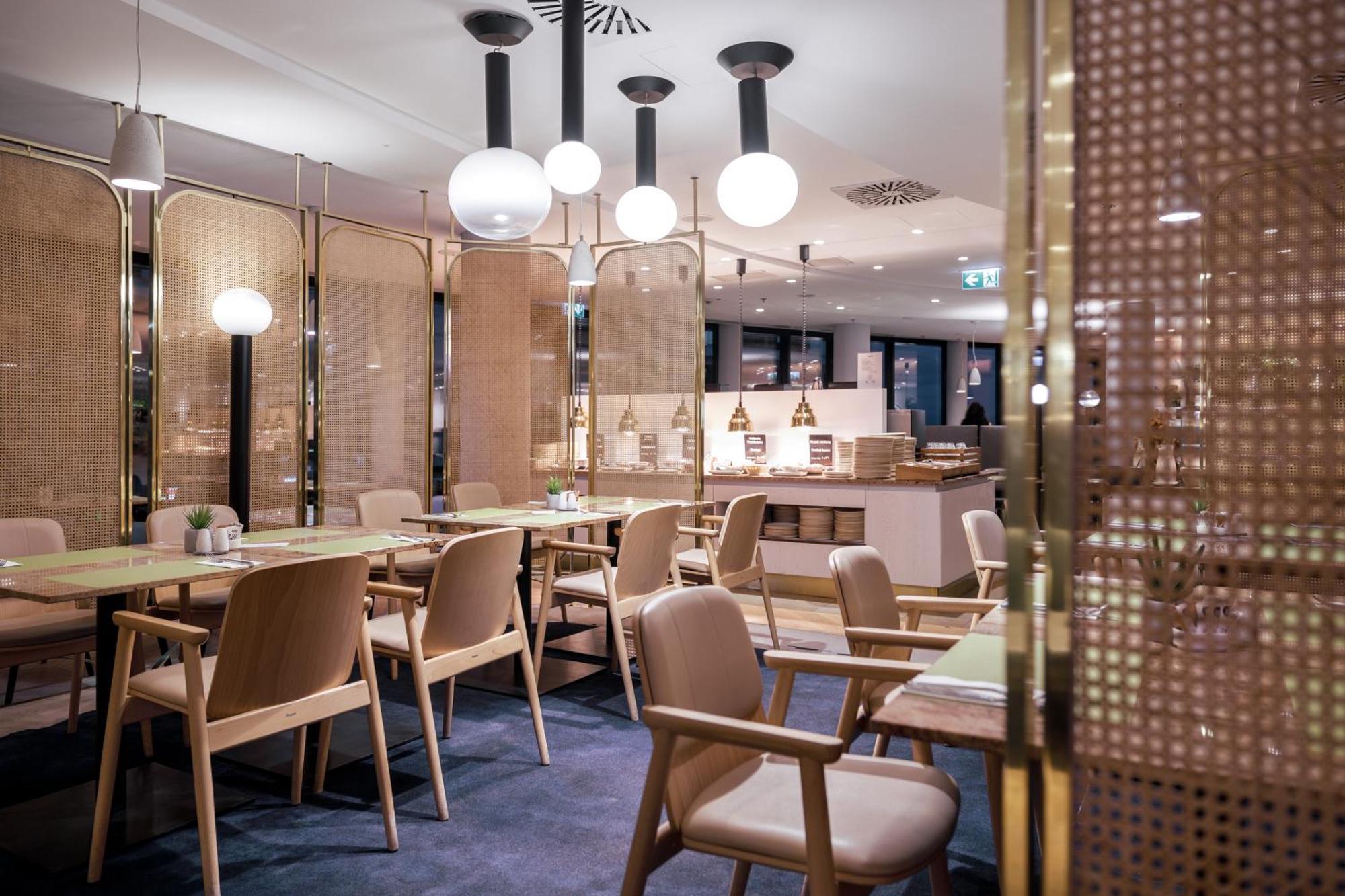 Radisson Blu Resort ชวีโนวิชแจ ภายนอก รูปภาพ The photo shows a modern restaurant interior. There are wooden tables and chairs arranged neatly. The atmosphere appears warm and inviting, with soft lighting provided by round pendant lamps hanging from the ceiling. Partitions made of woven material