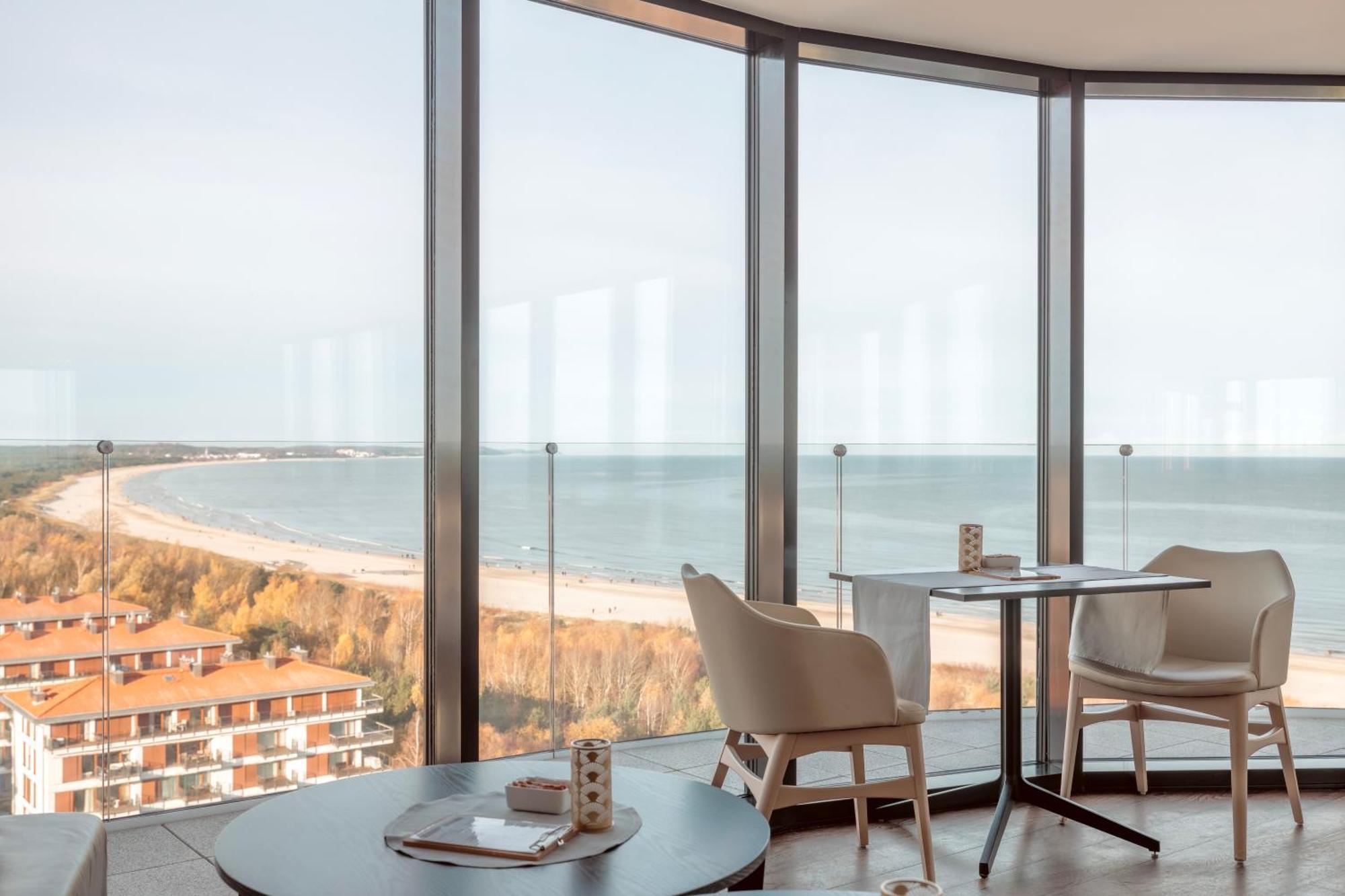 Radisson Blu Resort ชวีโนวิชแจ ภายนอก รูปภาพ The photo shows a modern interior space with large floor-to-ceiling windows that provide a stunning view of the beach and sea. The area appears to be a dining or lounge space, featuring a minimalistic table and chairs. There is a sense of tranquility