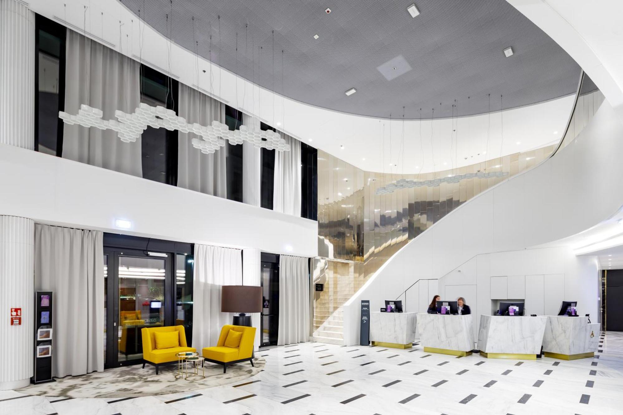 Radisson Blu Resort ชวีโนวิชแจ ภายนอก รูปภาพ The photo shows a modern interior space, likely a hotel or a lobby area. It features a spacious, open design with high ceilings and a stylish staircase that leads to an upper level. The walls are mostly white, with large windows allowing natural ligh