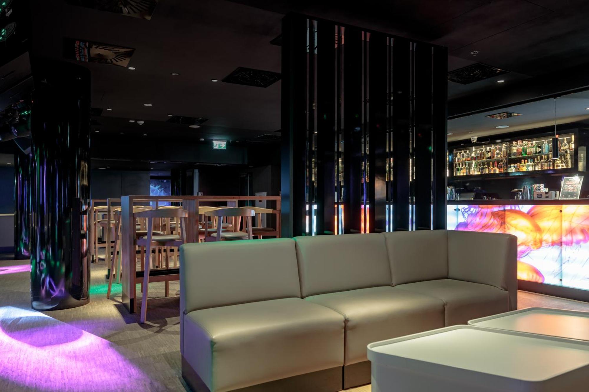 Radisson Blu Resort ชวีโนวิชแจ ภายนอก รูปภาพ The photo shows the interior of a stylish lounge or bar. The space features a modern design with dark walls and a sleek atmosphere. There is a beige sectional sofa in the foreground, providing a casual seating area. In the background, a bar is visibl