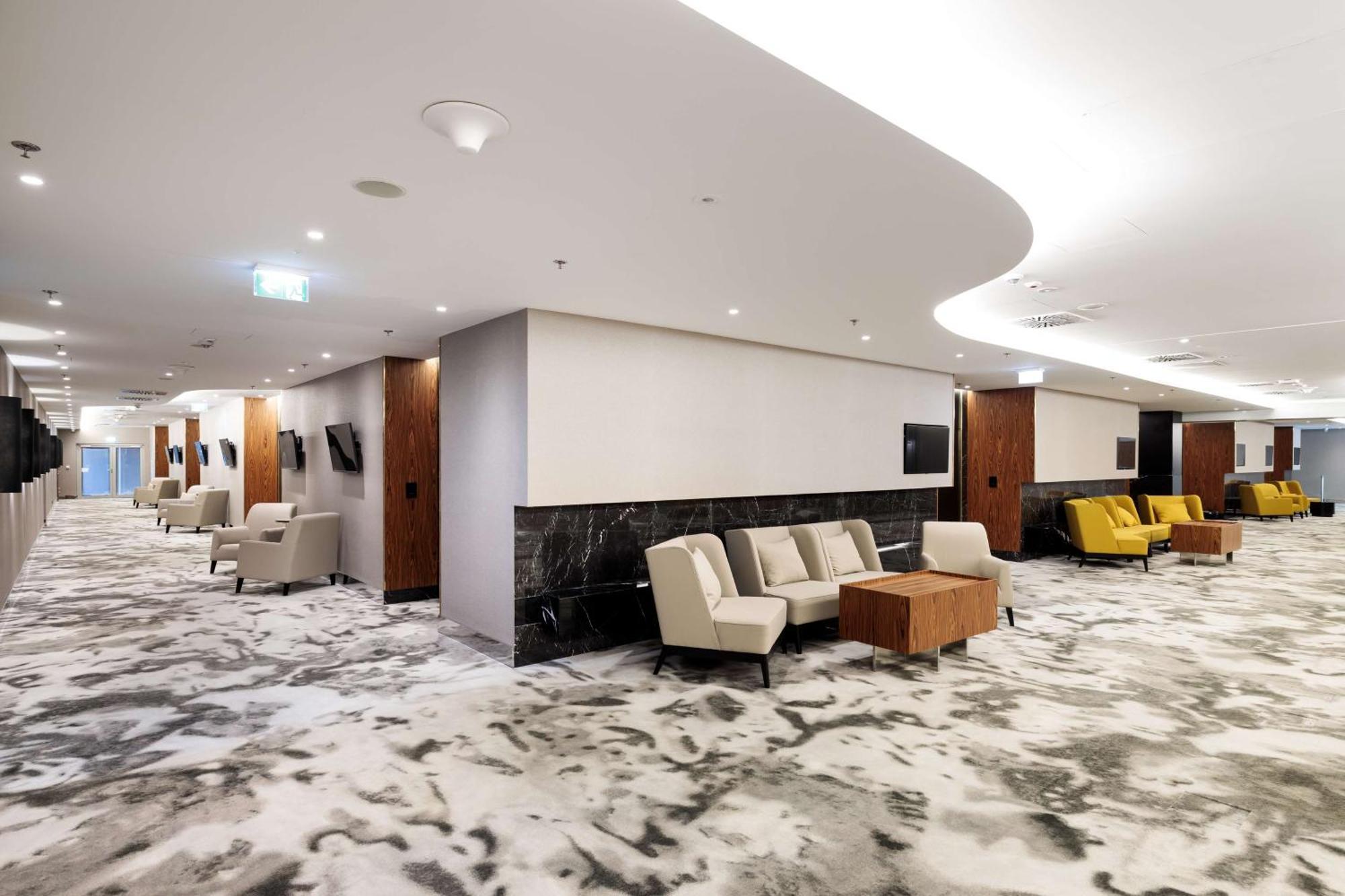 Radisson Blu Resort ชวีโนวิชแจ ภายนอก รูปภาพ The photo shows a modern interior space, likely a lobby or lounge area. The flooring features a patterned carpet, and the walls are neutral in color, creating a calm ambiance. There are comfortable seating arrangements, including a group of beige cha