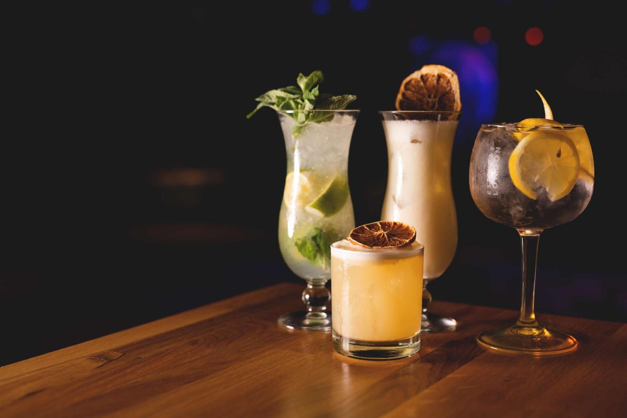 Radisson Blu Resort ชวีโนวิชแจ ภายนอก รูปภาพ The photo showcases a collection of four different cocktails displayed on a wooden table. 

1. **Mojito**: A tall glass filled with lime slices, mint leaves, and a clear liquid, likely rum-based, garnished with fresh mint.
2. **Creamy Cocktail**: A s