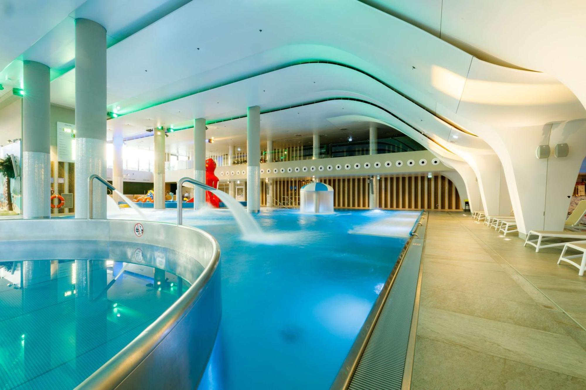 Radisson Blu Resort ชวีโนวิชแจ ภายนอก รูปภาพ The photo shows a modern indoor swimming pool area with an elegant design. The pool features curved edges and is filled with clear, blue water. There are various amenities, such as jets for relaxation and possibly seating areas along the edges. The l