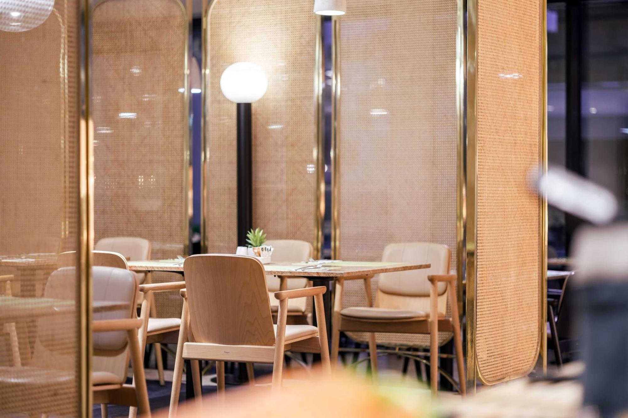 Radisson Blu Resort ชวีโนวิชแจ ภายนอก รูปภาพ The image shows an interior space, likely part of a restaurant or café. There are several wooden chairs arranged around tables, and the overall decor features soft lighting and warm colors. The walls appear to be partially covered with a woven materi
