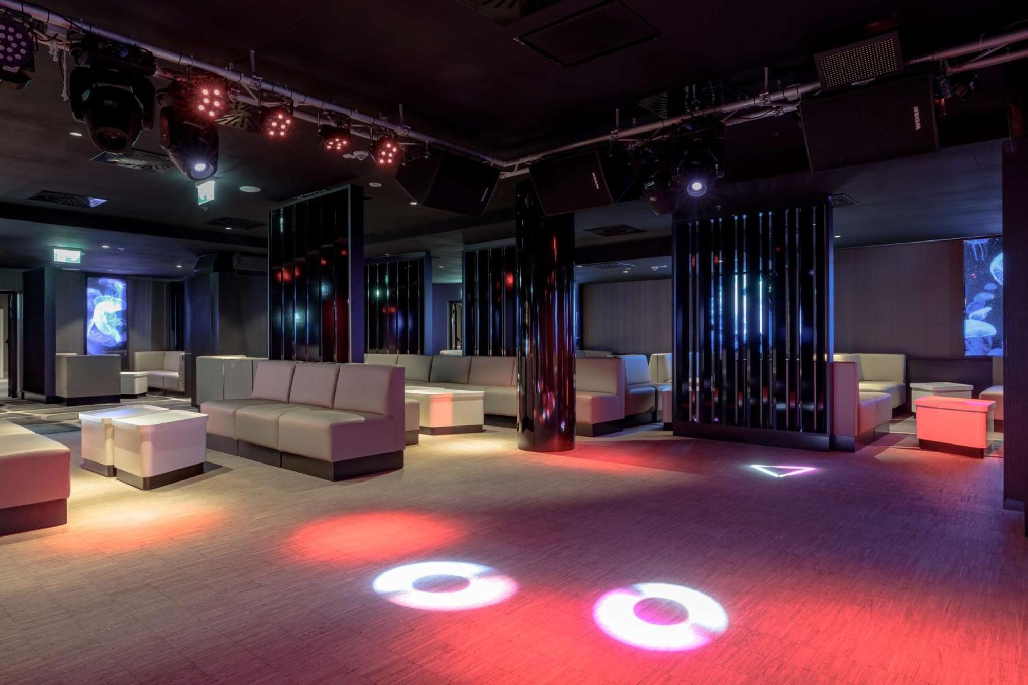Radisson Blu Resort ชวีโนวิชแจ ภายนอก รูปภาพ The photo depicts a modern nightclub interior, featuring a spacious layout with sleek, minimalist seating arrangements. The room has plush seating along the walls, and the floor is illuminated with circular lights in varying colors, creating a vibran