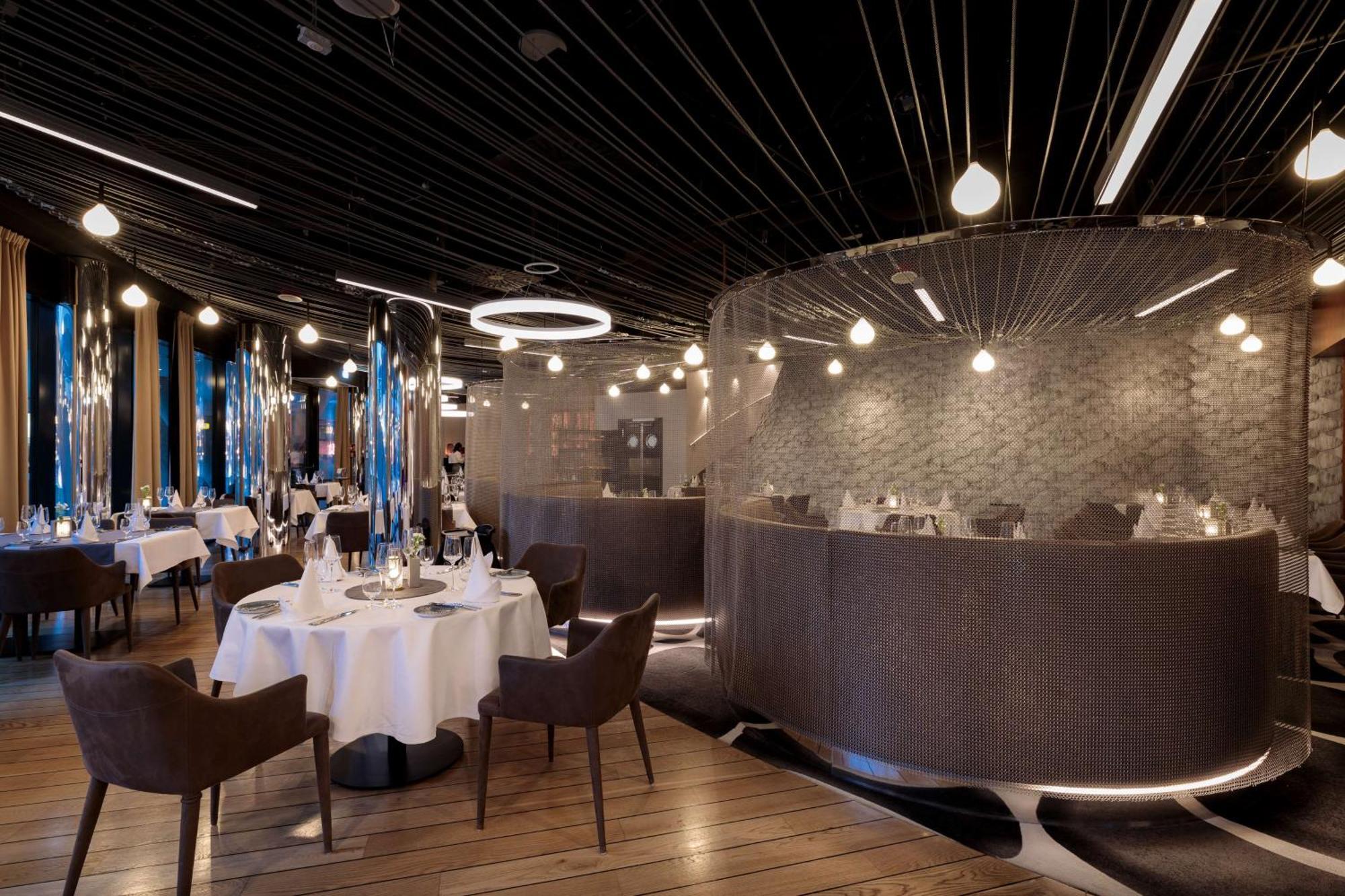 Radisson Blu Resort ชวีโนวิชแจ ภายนอก รูปภาพ The photo shows an elegant restaurant interior. It features polished wooden floors and contemporary decor. Round tables are set with white tablecloths and have chairs arranged around them. The lighting is modern, with multiple pendant lights hanging 