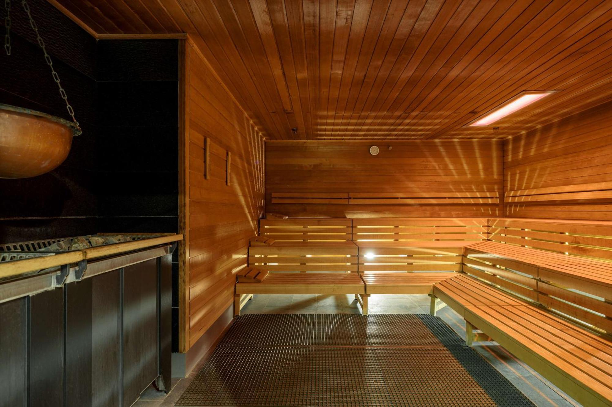 Radisson Blu Resort ชวีโนวิชแจ ภายนอก รูปภาพ The photo shows the interior of a sauna. The walls and benches are made of wood, creating a warm and inviting atmosphere. There is a heater, likely for generating steam, and a metal rack connected to it, perhaps for holding stones or water. The desig