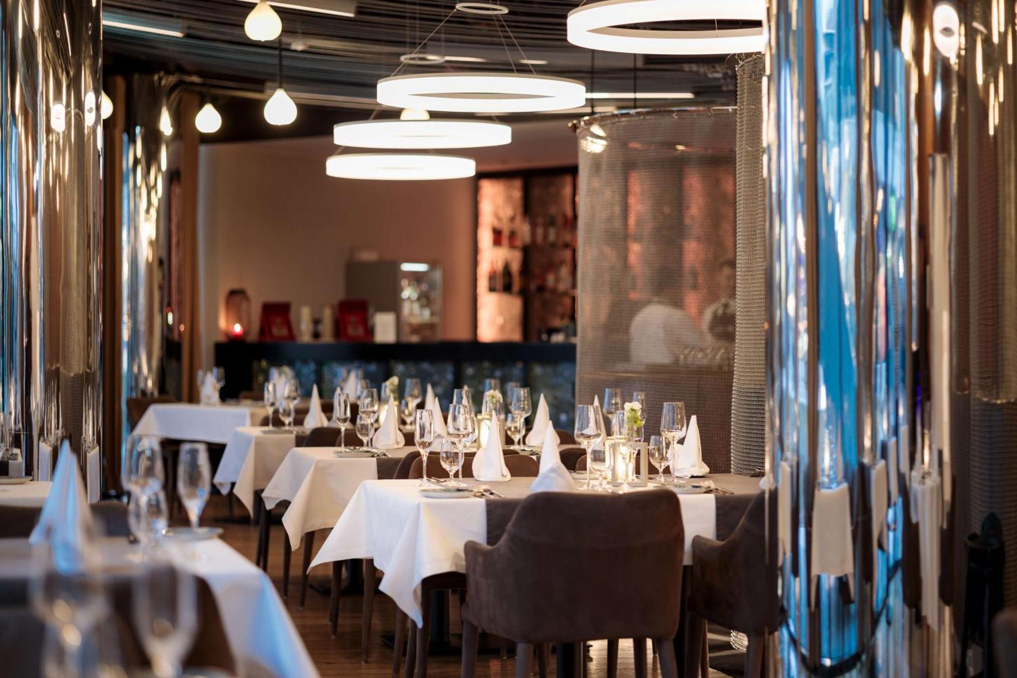 Radisson Blu Resort ชวีโนวิชแจ ภายนอก รูปภาพ The photo depicts an elegant restaurant interior. There are several tables covered with white tablecloths, each set with glassware and napkins, suggesting a fine dining experience. The chairs are upholstered, providing a comfortable seating arrangeme