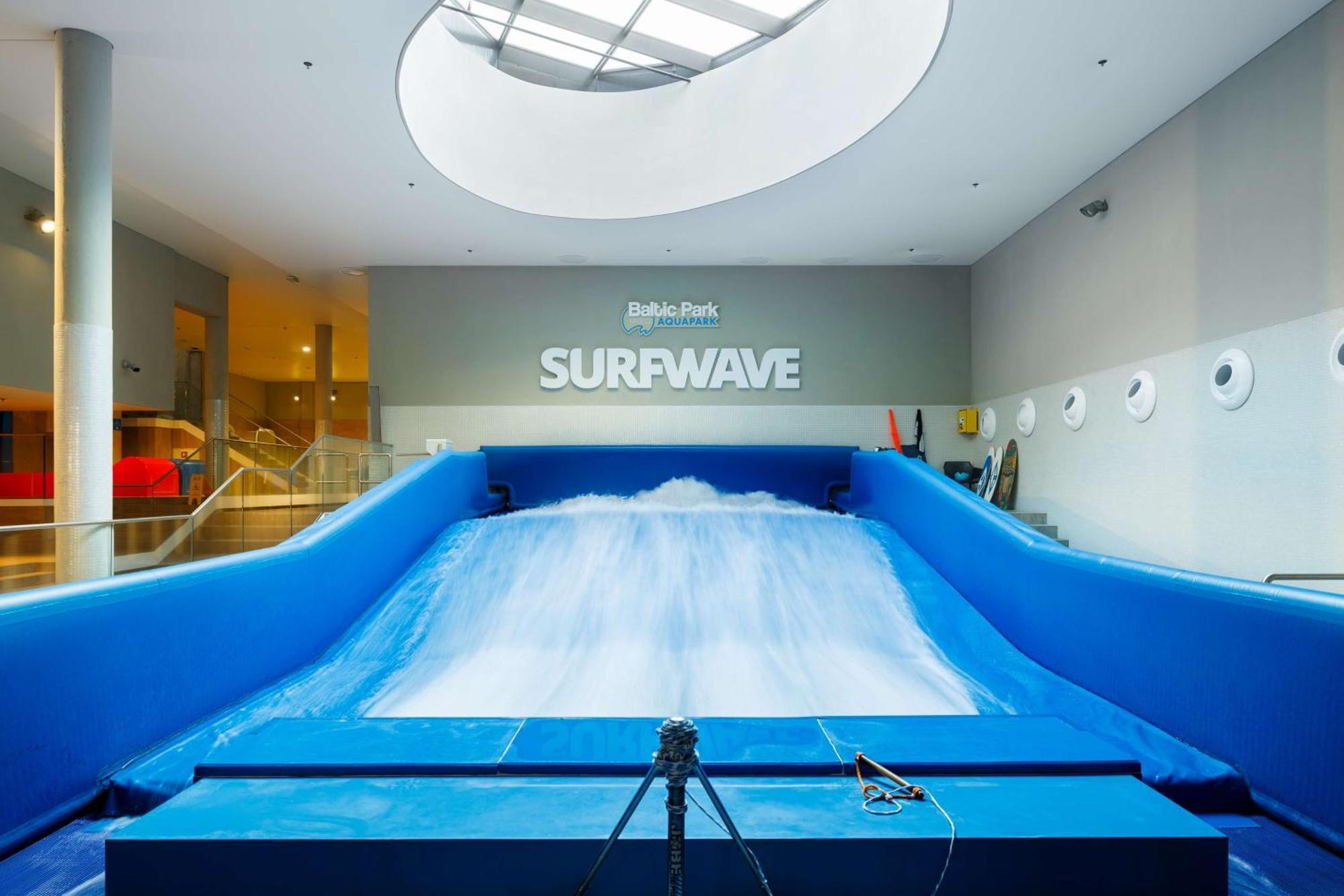 Radisson Blu Resort ชวีโนวิชแจ ภายนอก รูปภาพ The photo shows an indoor surfing attraction called "Surfwave." It features a large blue ramp with water flowing down it, creating a wave-like effect for surfing. Above the ramp, there is a sign that says "SURFWAVE." The area appears well-lit and mod